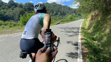 Cyklista podává druhému cyklistovi gel Nrgy