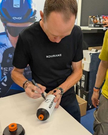 Chris Froome podepisuje lahev Nduranz na Eurobike 2025